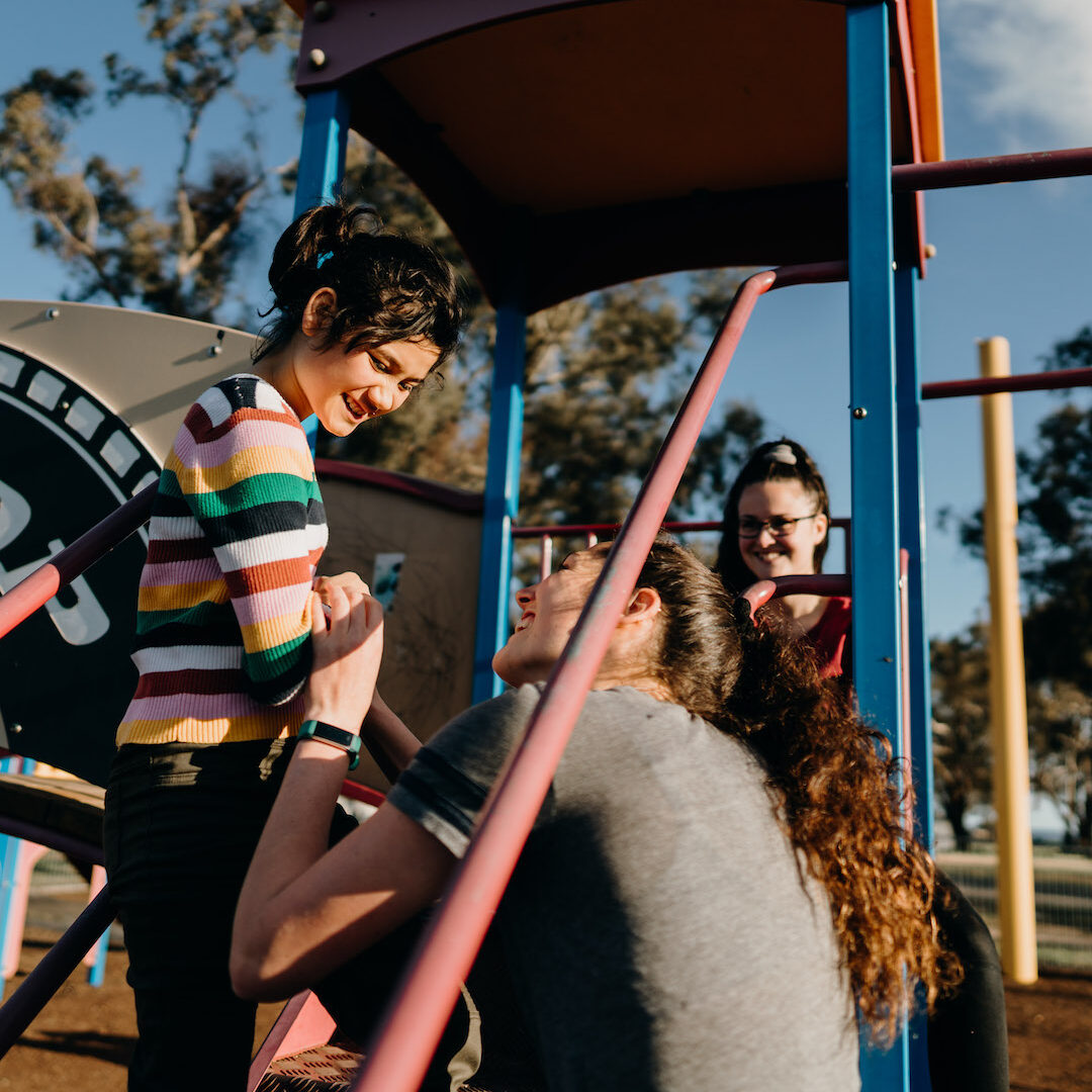 image of young girl on play equipment with carers