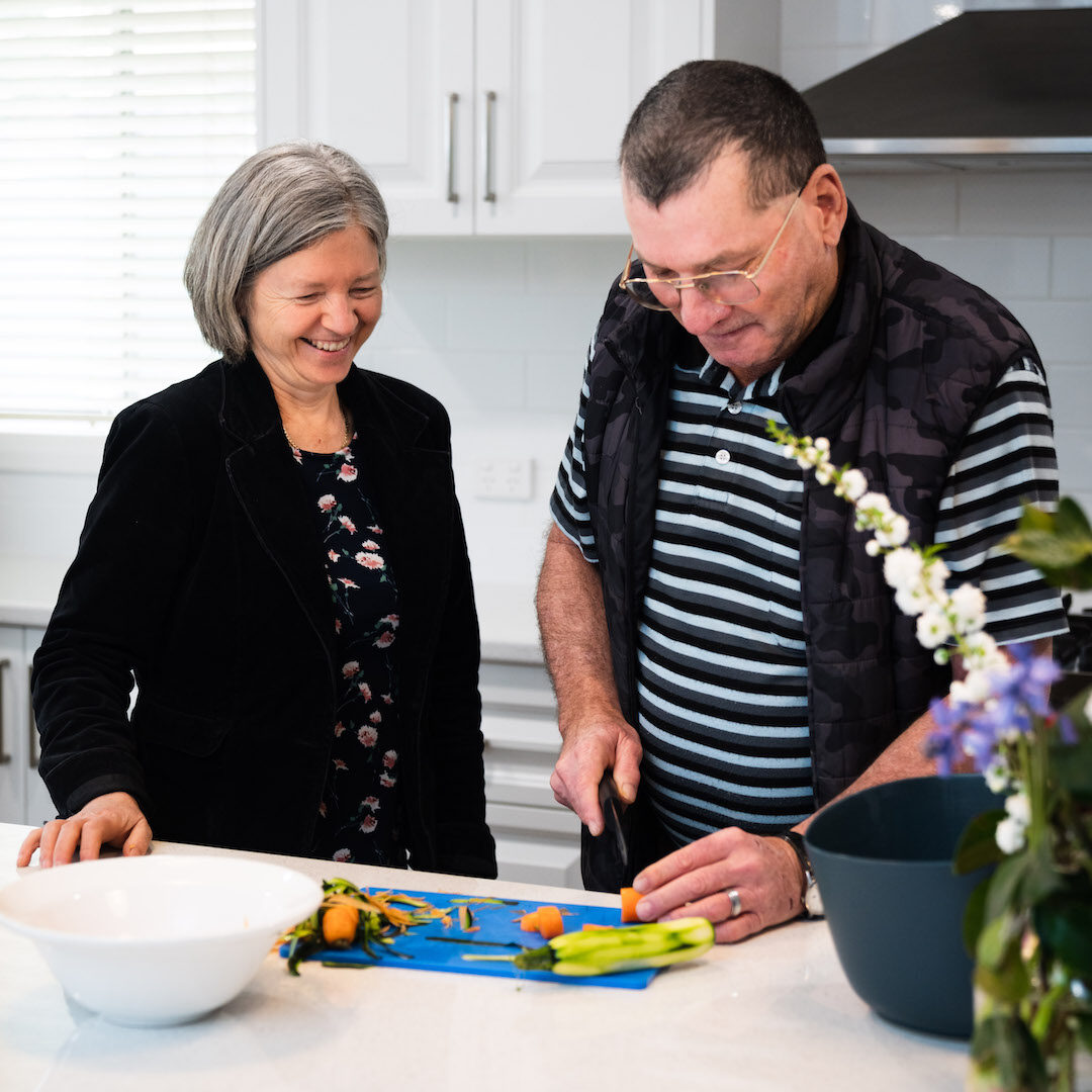 woman watching man to cut vegetables in kitchen